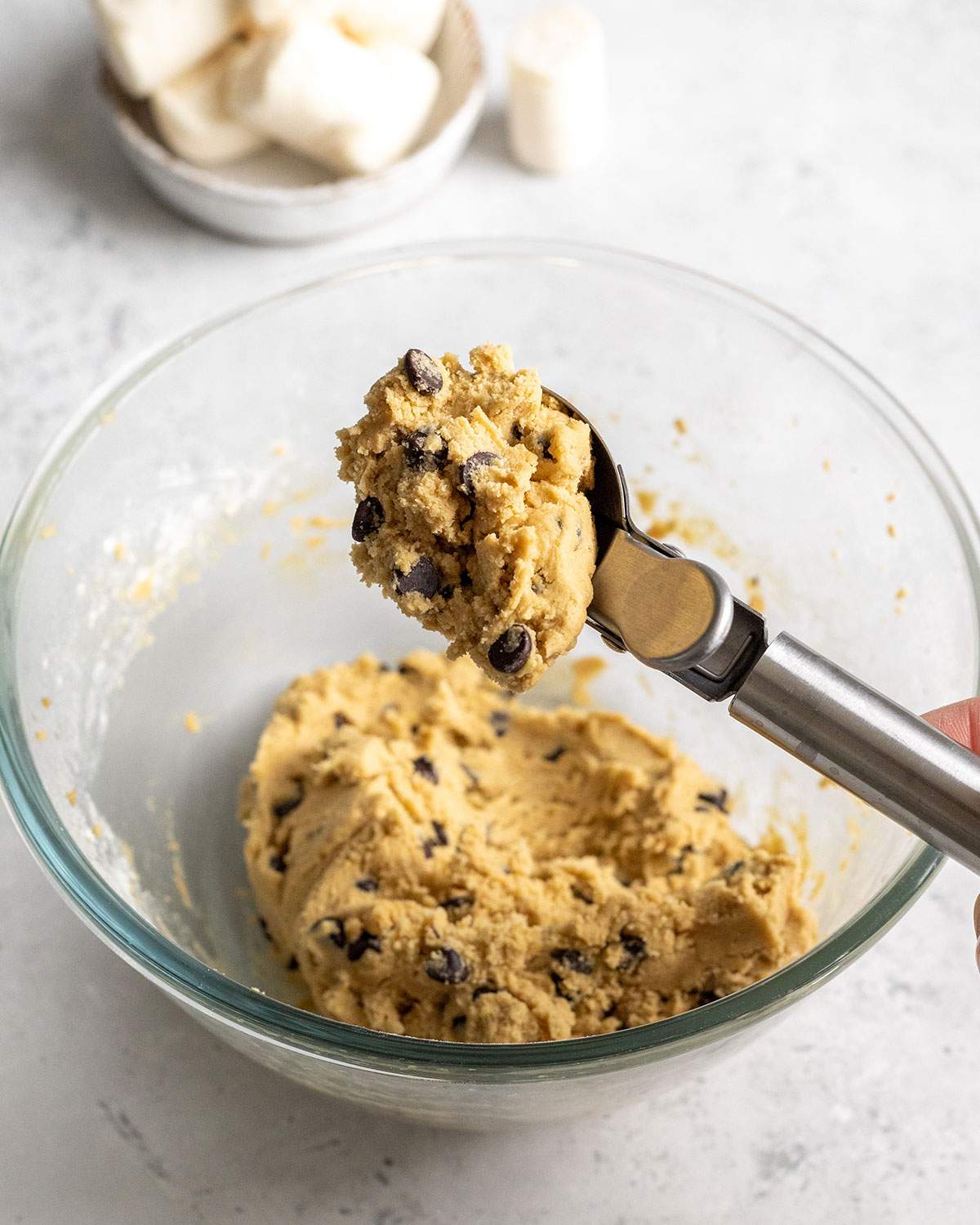 a scoop picking up cookie dough from a mixing bowl