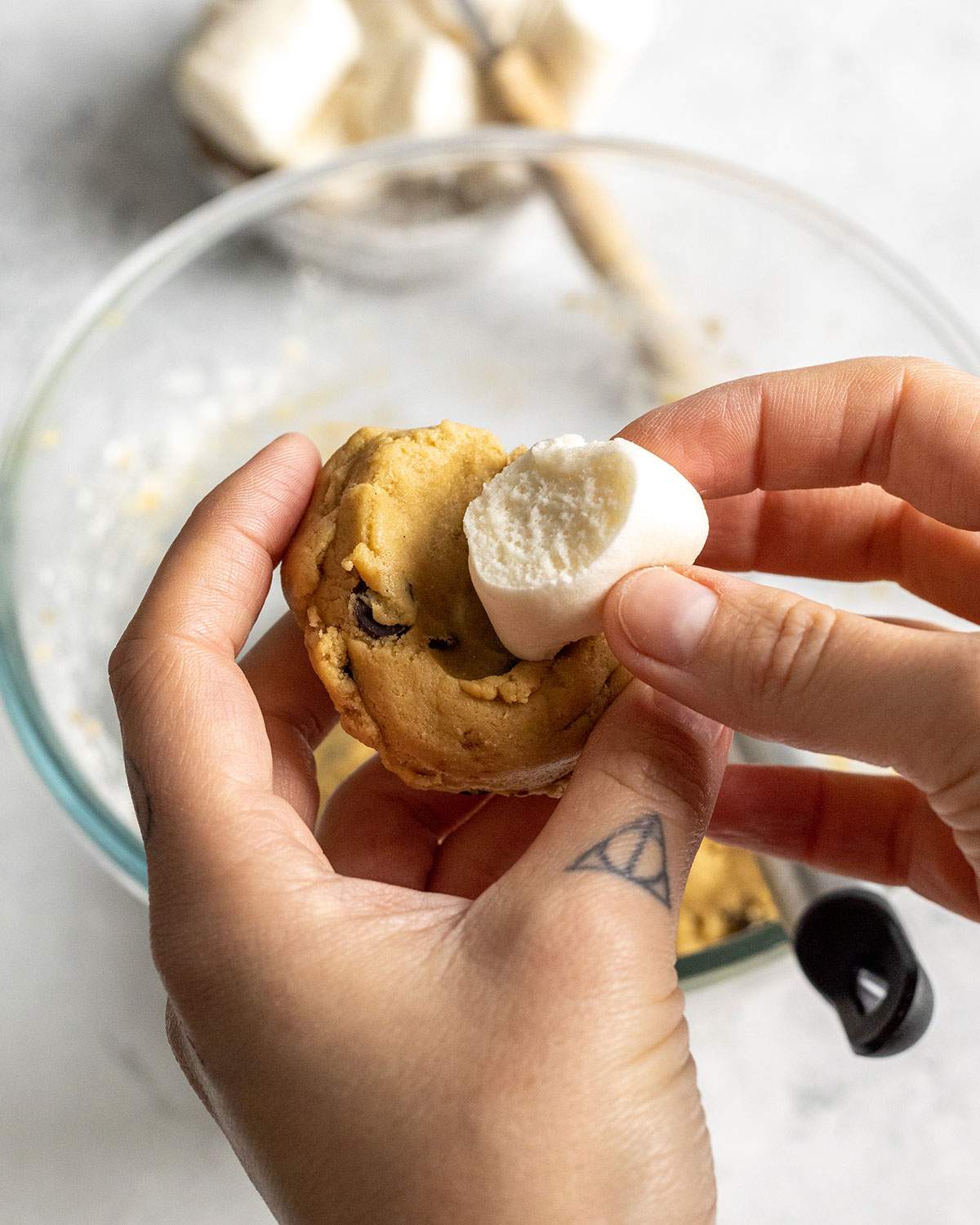 adding a vegan marshmallow to the hole in a cookie dough ball