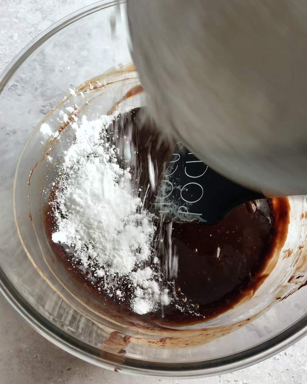 adding confectioner's sugar to a bowl of chocolate ganache