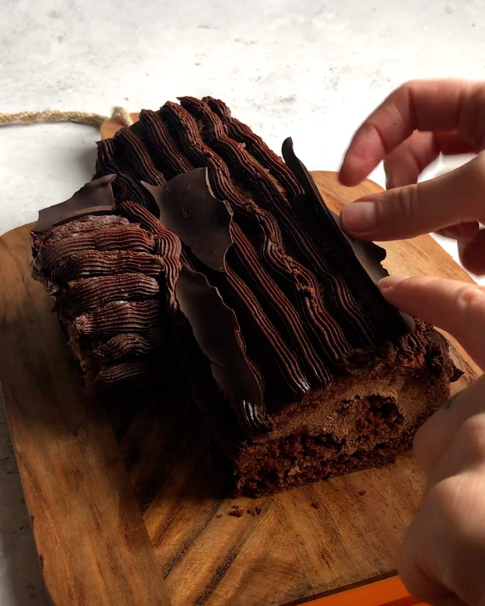 attaching vegan chocolate bark to the soft chocolate coating of a yule log