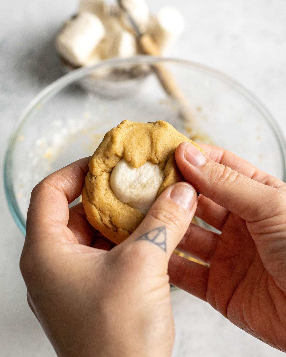 covering a marshmallow in the middle of a cookie dough ball with cookie dough