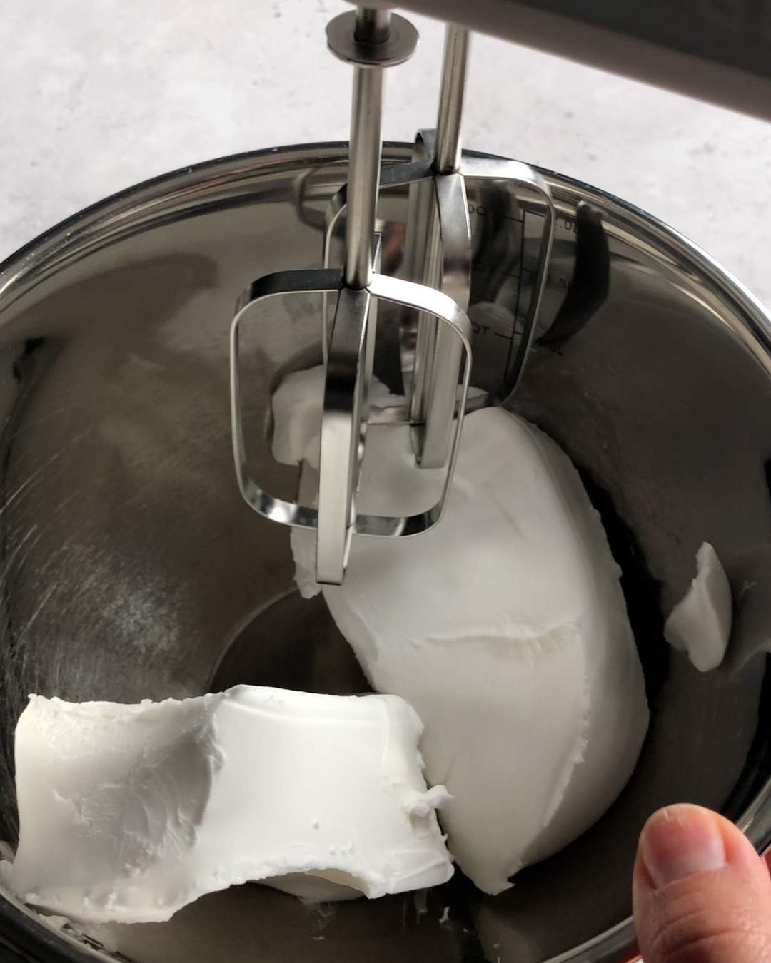 cream cheese in a mixing bowl with an electric mixer