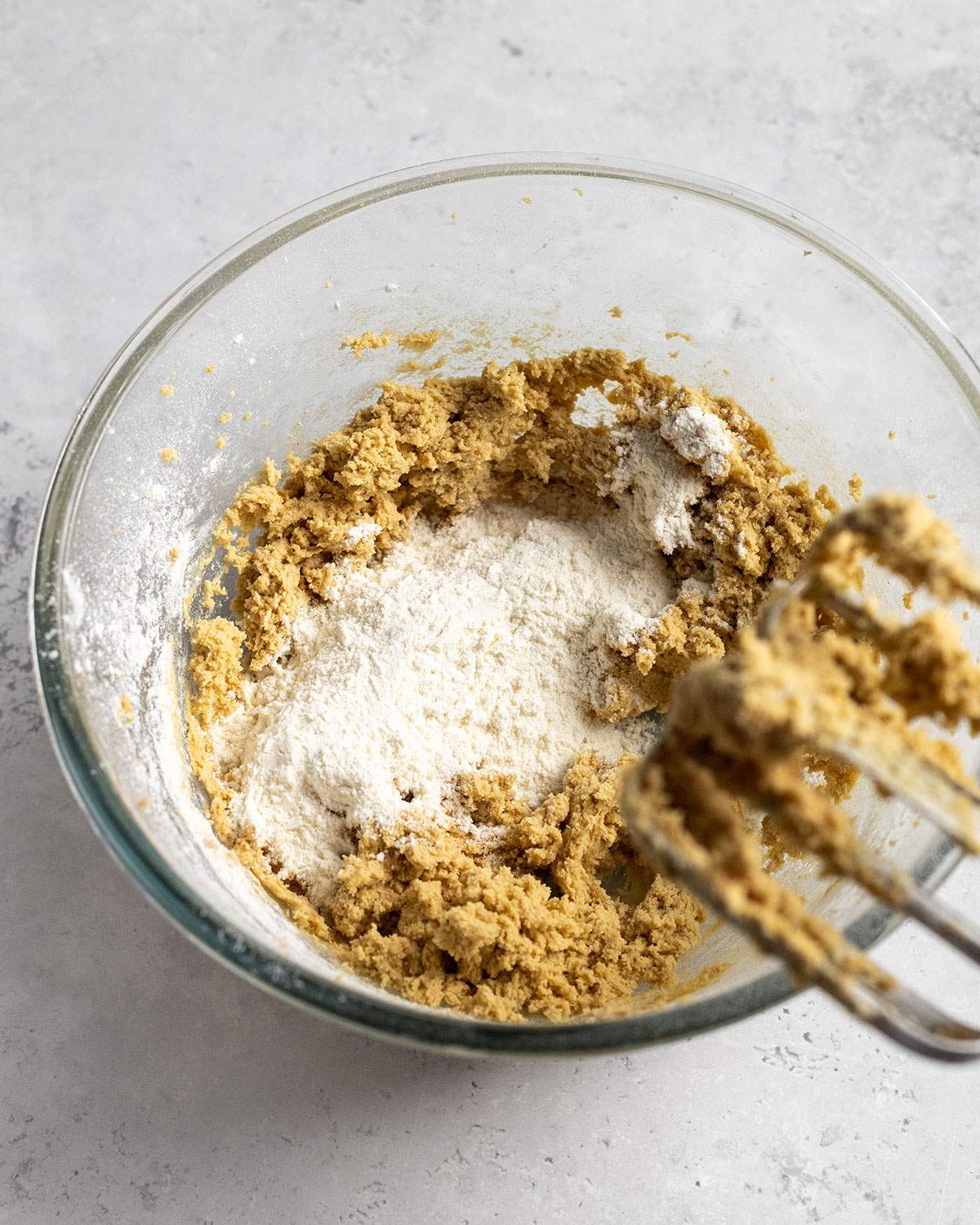 dry ingredients added to a bowl of creamed butter and sugar