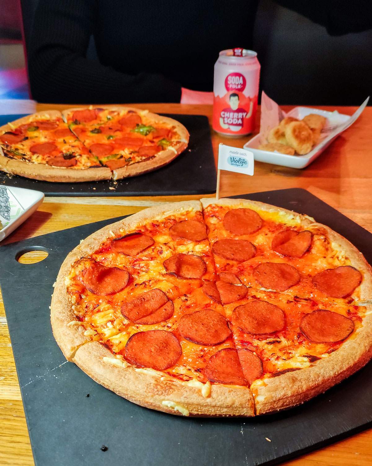 2 vegan pizzas, 1 portion of vegan nuggets and a can of soda on a table at pizza hut