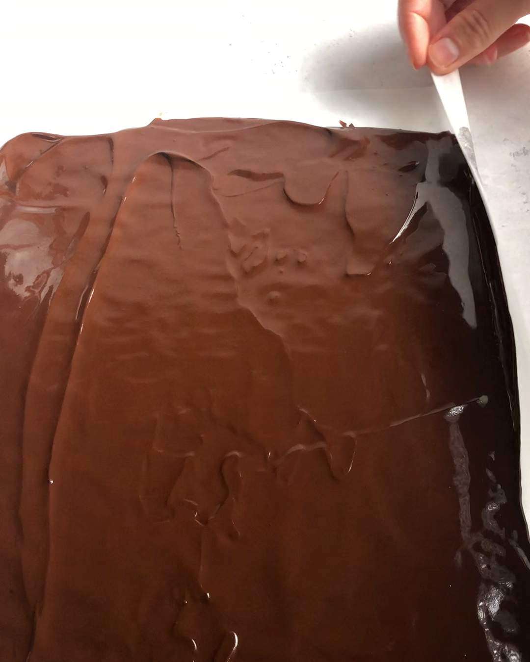 rolling up the edges of a chocolate covered parchment paper