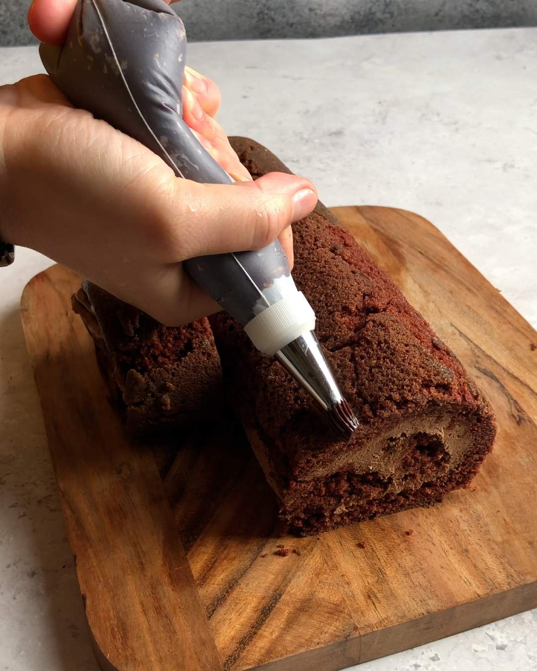 squeezing vegan chocolate cream on top of the vegan yule log