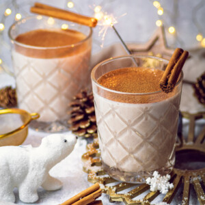 2 glasses of oat milk eggnog on a festive table setup with a cute polar bear decoration