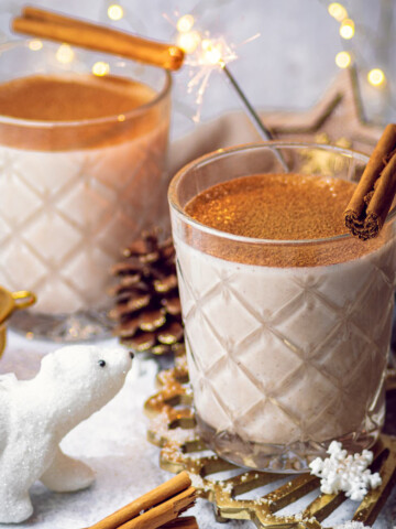 2 glasses of oat milk eggnog on a festive table setup with a cute polar bear decoration