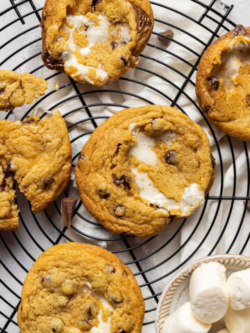 vegan smores cookies on a cooling rack with a small bowl of vegan marshmallows on the side