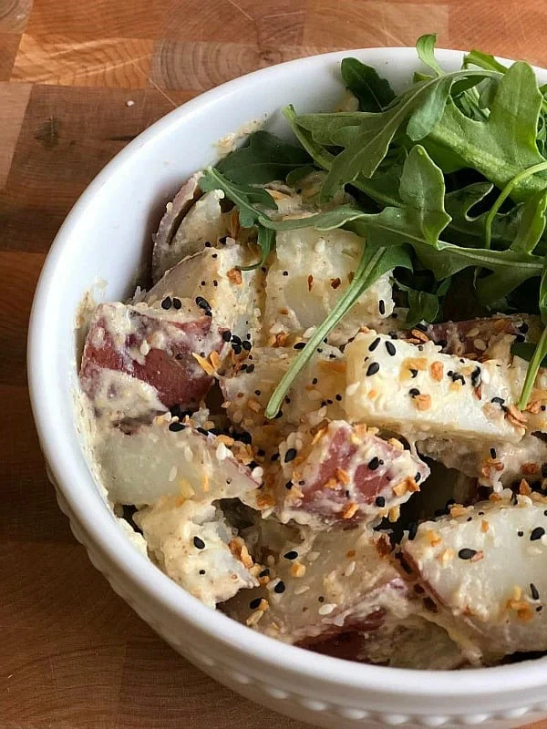 a bowl filled with vegan potato salad and everything bagel seasoning on top