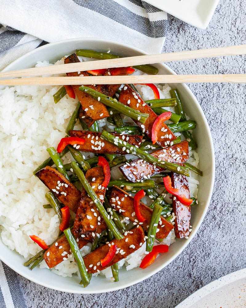 A bowl with rice and top with sticky teriyaki tofu