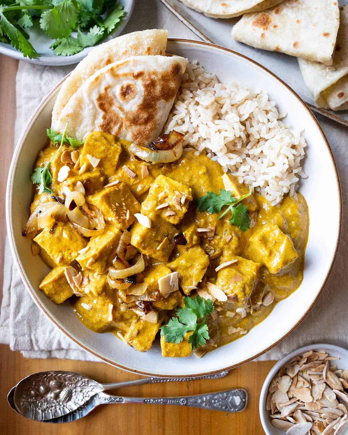 a beautiful bowl filled with rice, naan bread and tofu korma