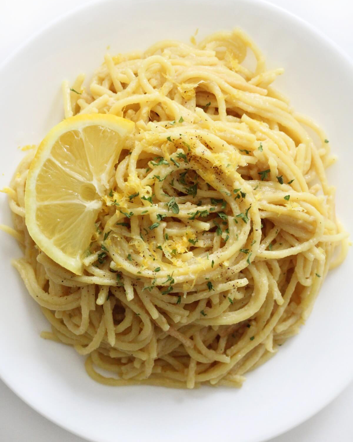 a white bowl filled with vegan pasta al limone