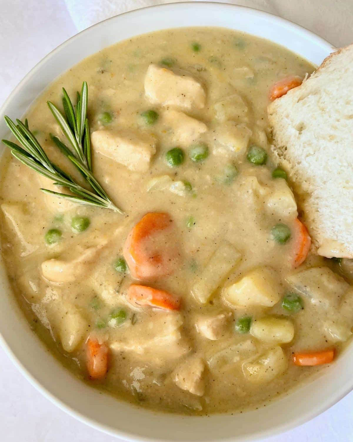 Vegan pie soup in a white bowl with fresh rosemary and a slice of bread