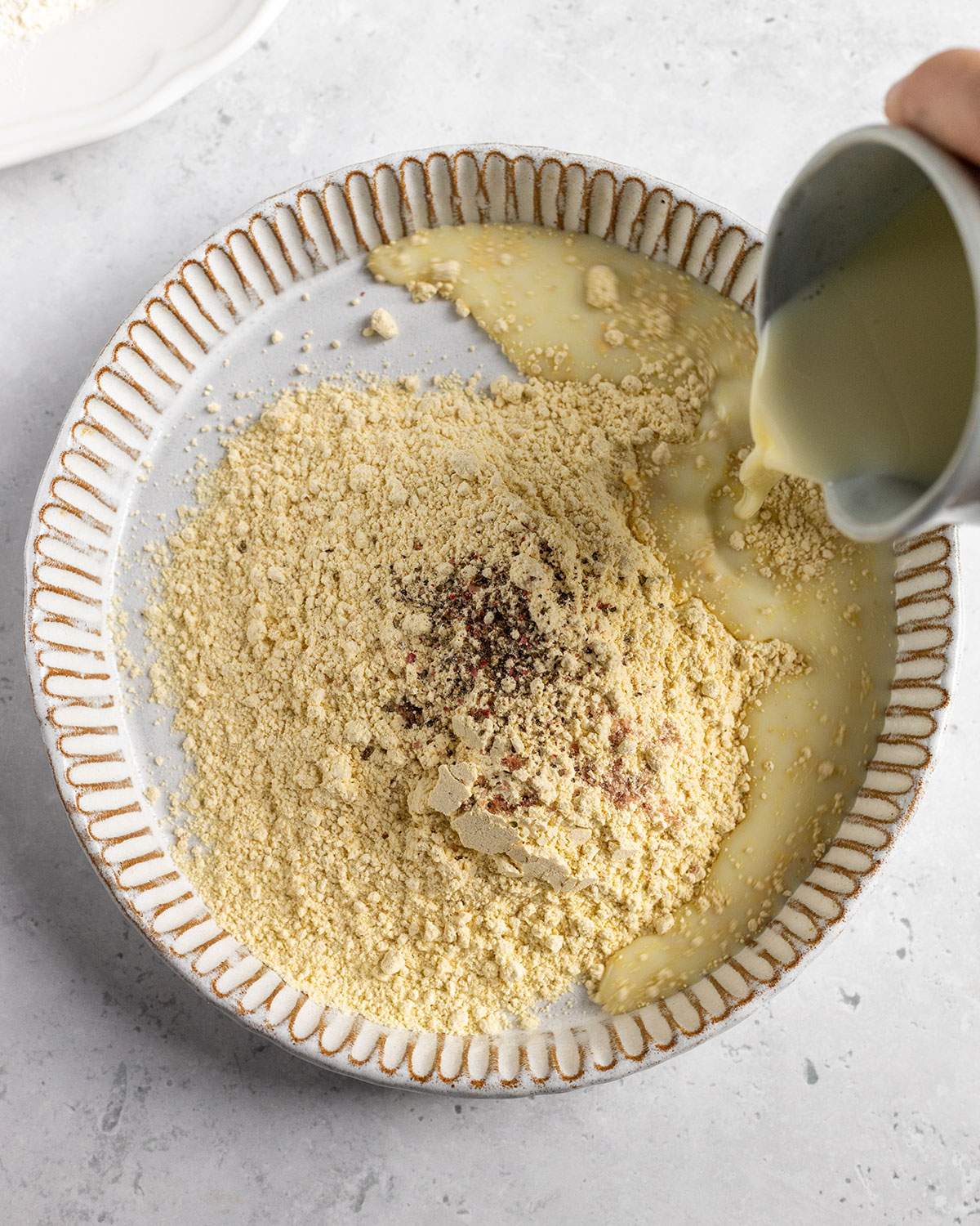 pouring plant milk into a bowl with ingredients