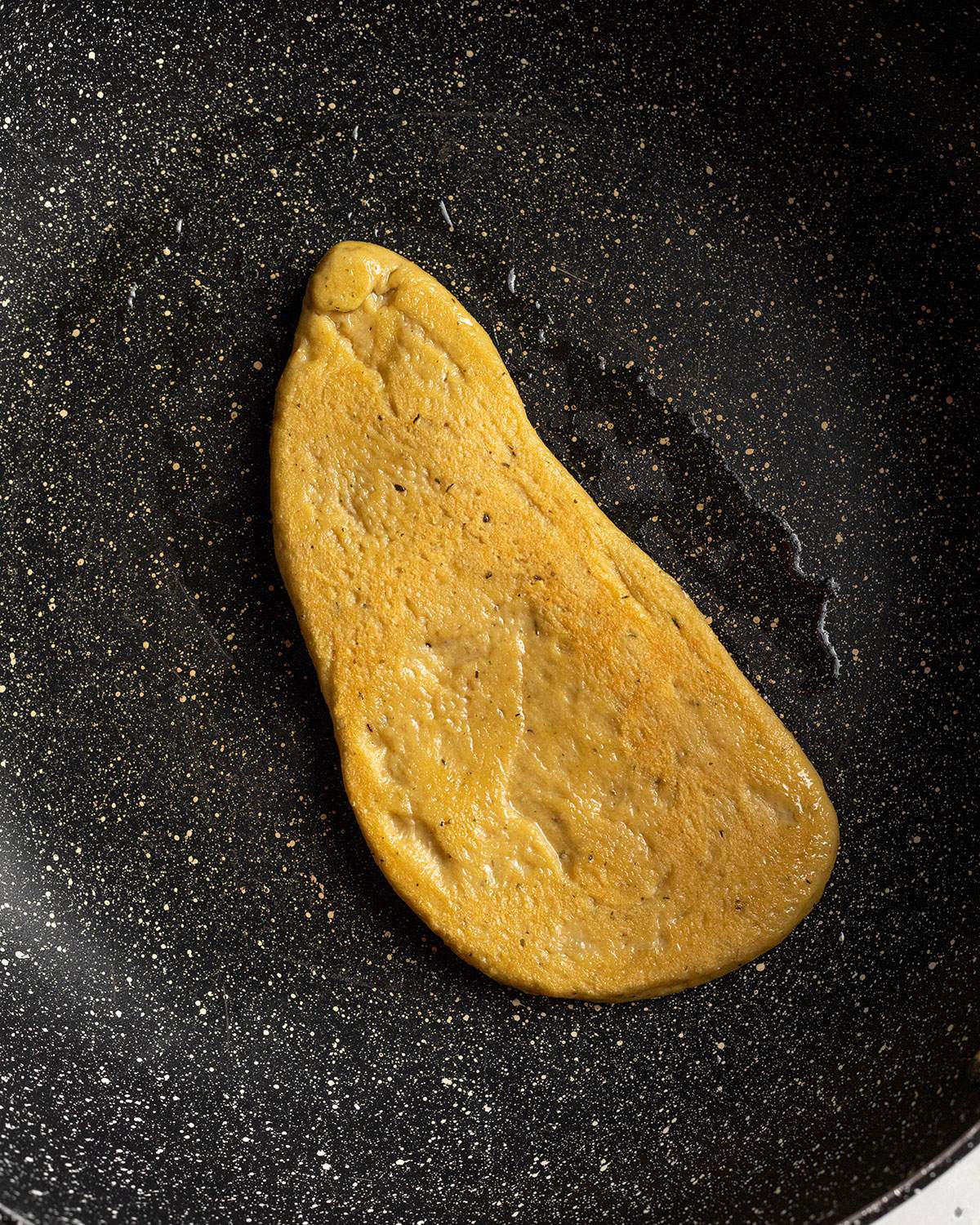 a seitan schnitzel panfrying in a bit of oil