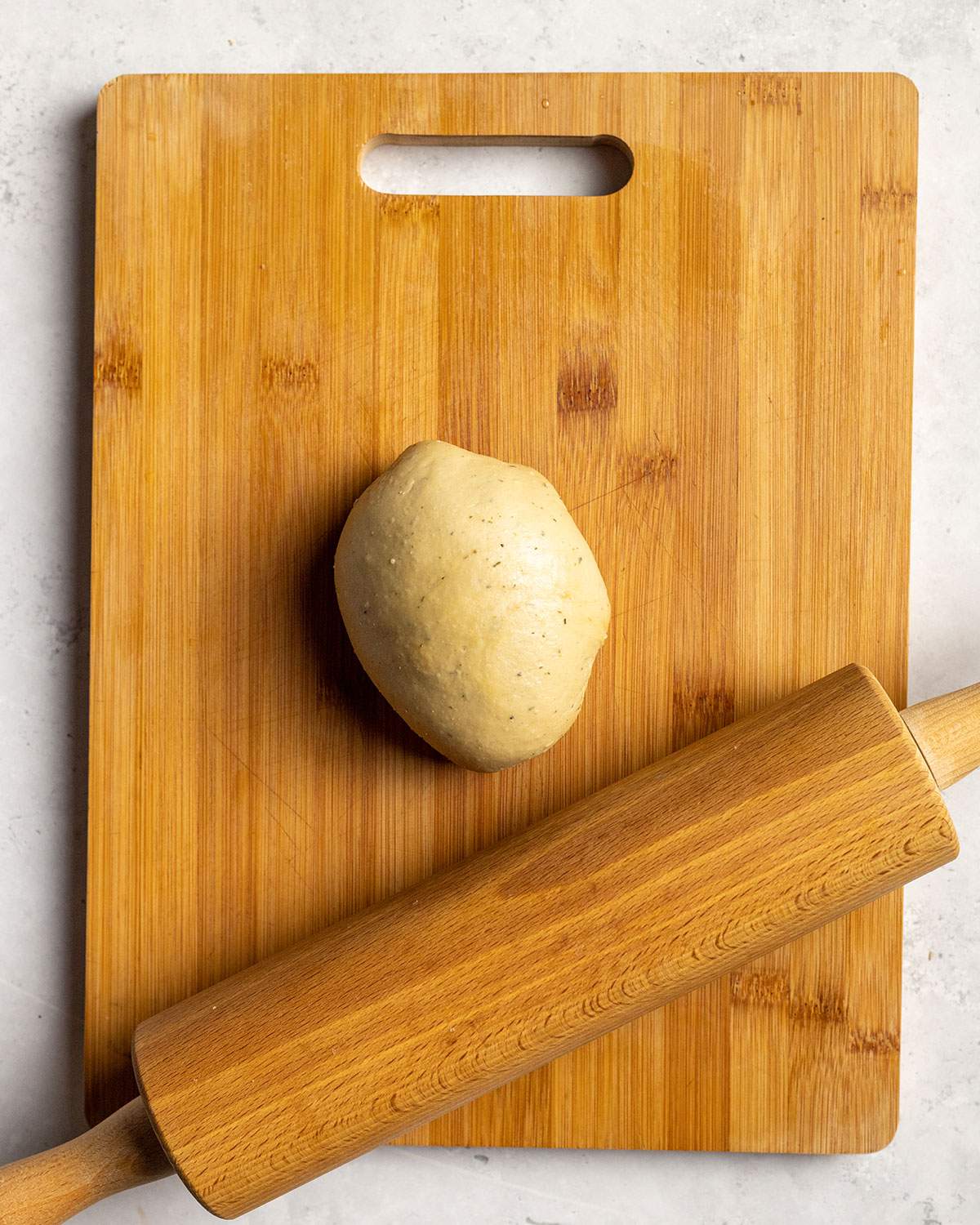 seitan dough ball with a rolling pin on a cutting board