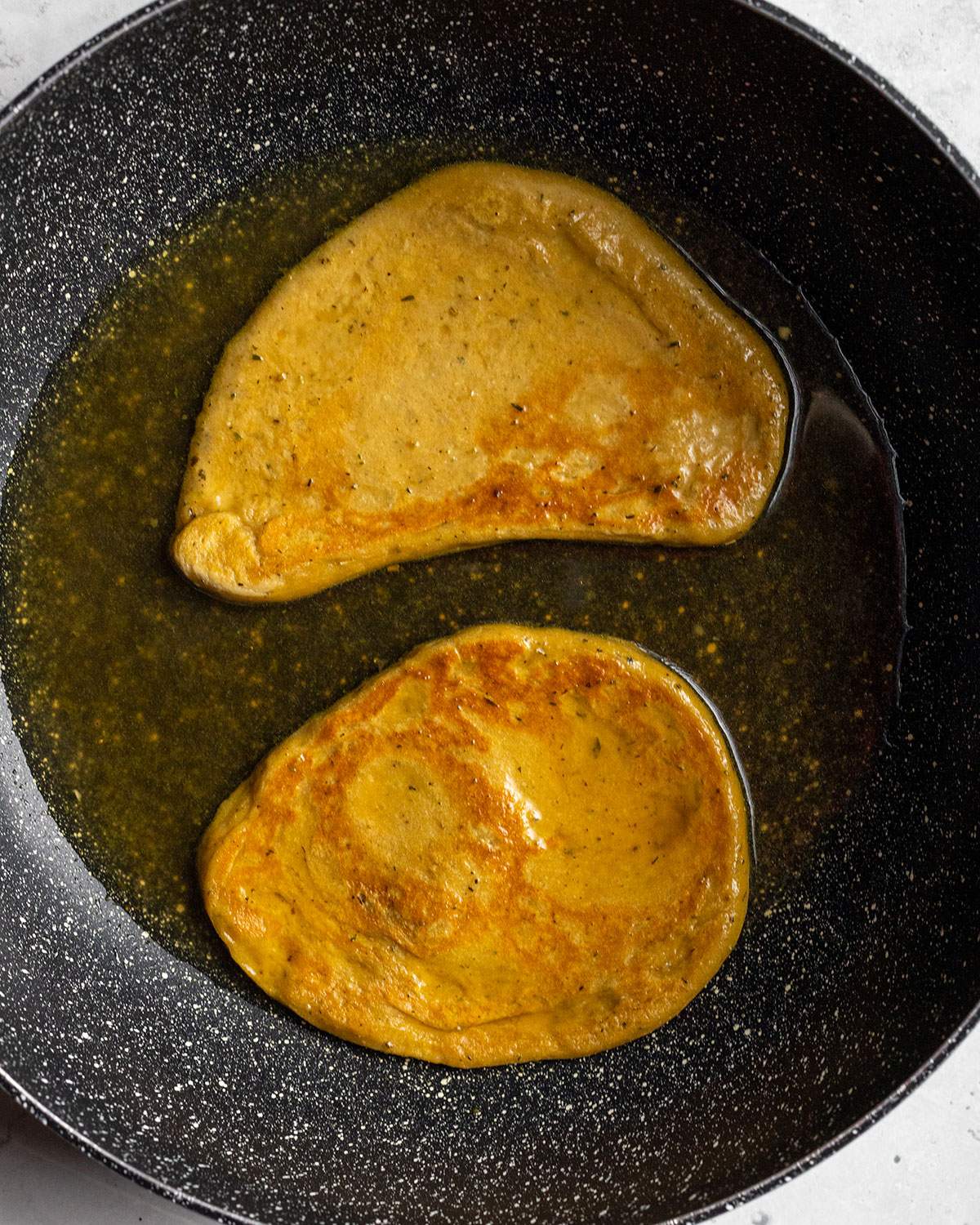 simmering vegan seitan schnitzels in vegetable broth in a big skillet_01