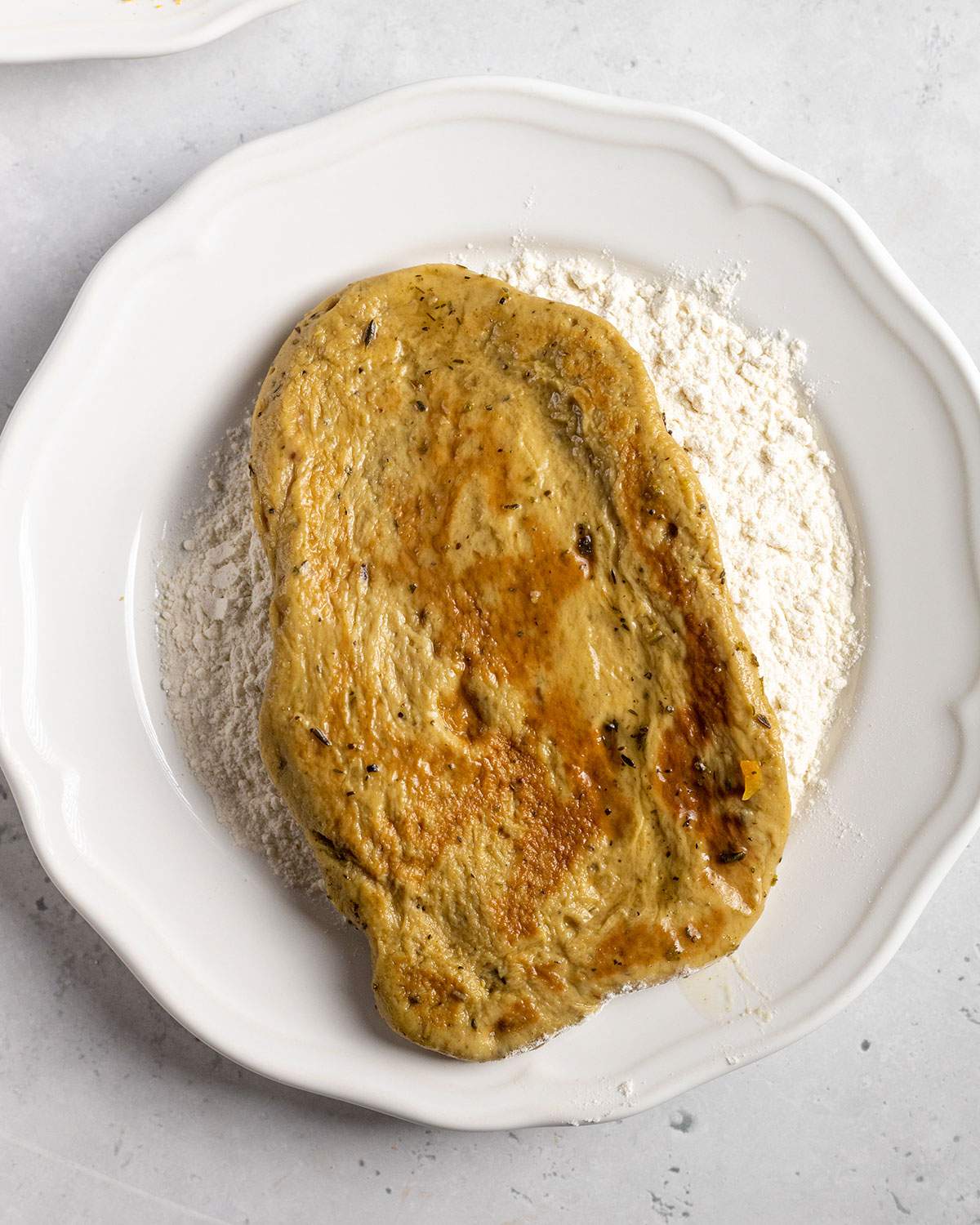 a vegan schnitzel on a white plate dusted with flour