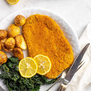 vegan schnitzel on a white place with vegetables and lemon slices