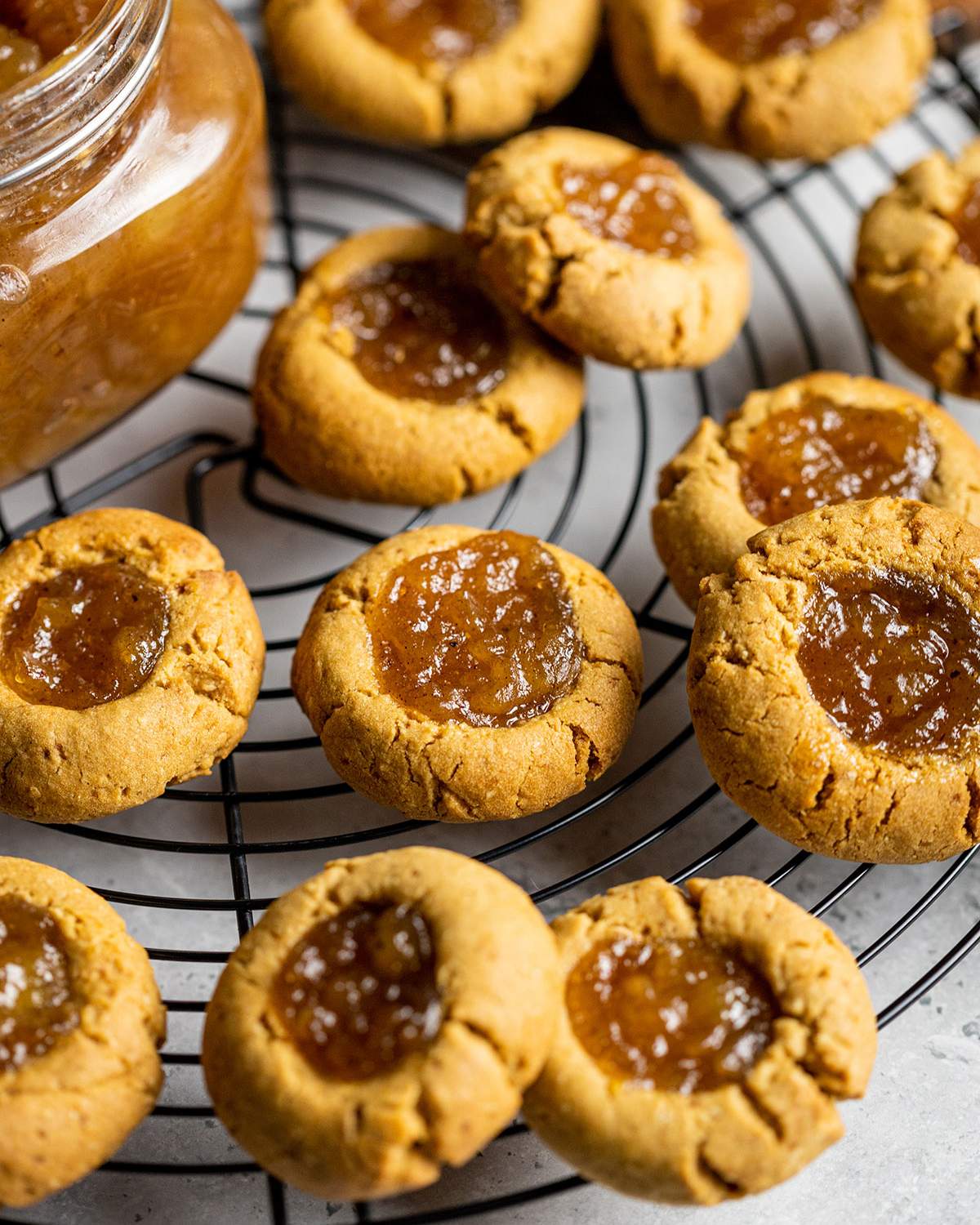 close up of vegan thumbprint cookies with apple pie jam on a cooling rack