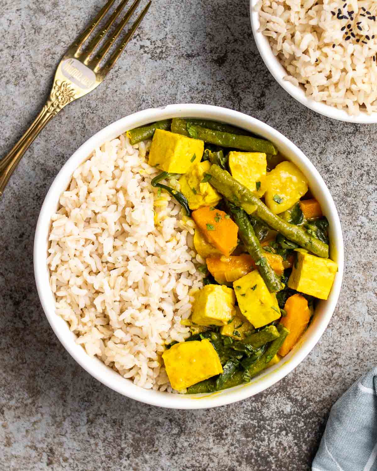 vegan yellow curry with rice in a white bowl on a dining table