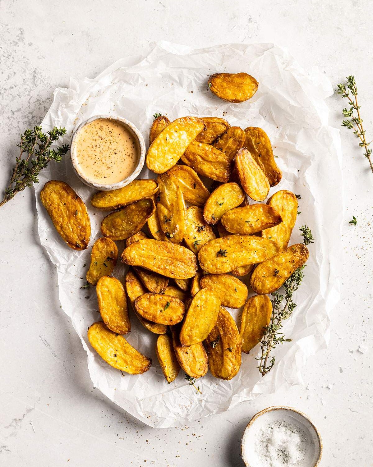 air fried fingerling potatoes on a white parchment with a dip on the side