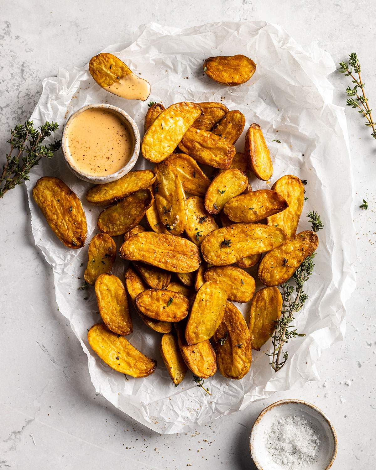 air fried fingerling potatoes on a white parchment with a dip on the side