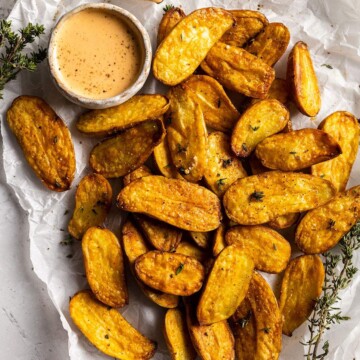 air fried fingerling potatoes on a white parchment with a dip on the side