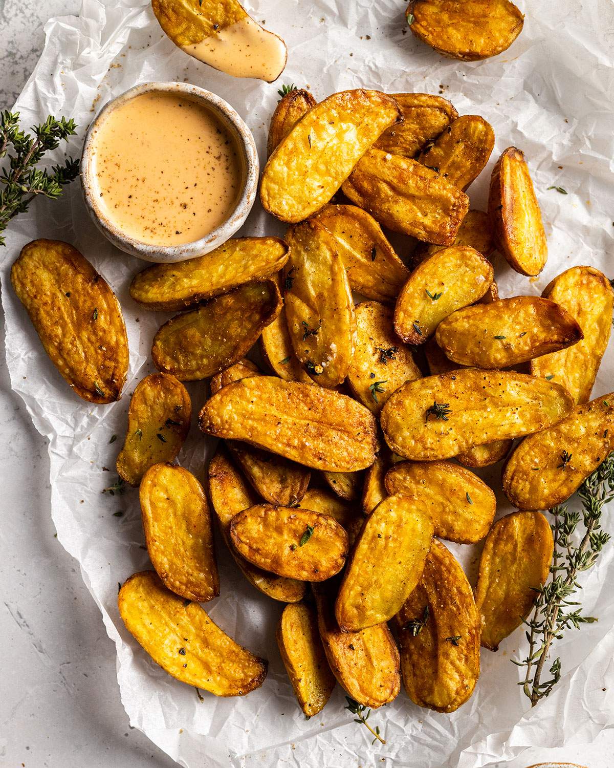 air fried fingerling potatoes on a white parchment with a dip on the side