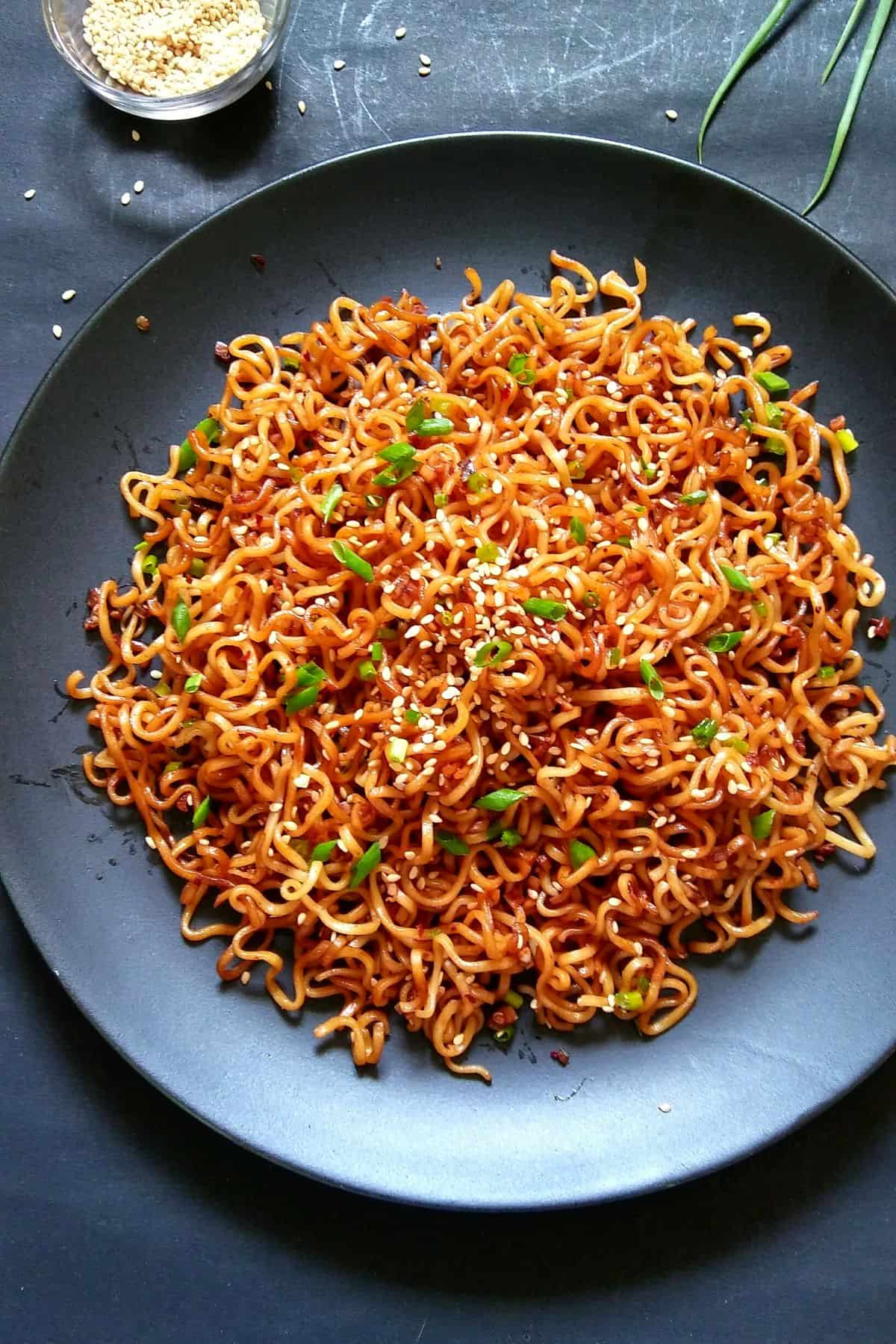 a black bowl filled with garlic sesame ramen noodles on a dark table