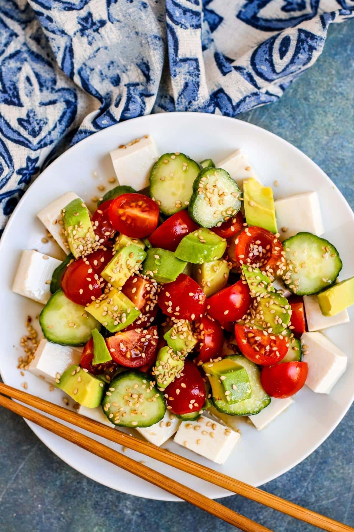 a white plate with silken tofu salad and chopsticks on the side