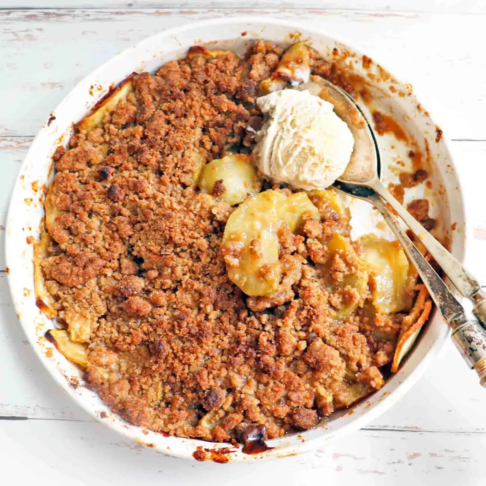 an oven dish filled with vegan apple crisp and ice cream on top