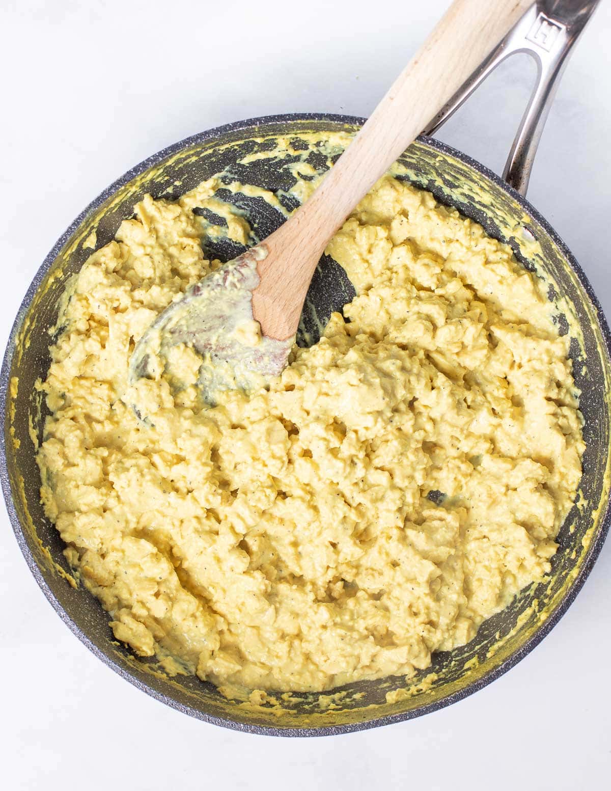 Vegan Scrambled Eggs in a skillet with a wooden spoon