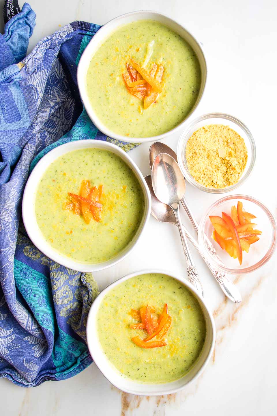 3 bowls of vegan zucchini soup on a dinner table