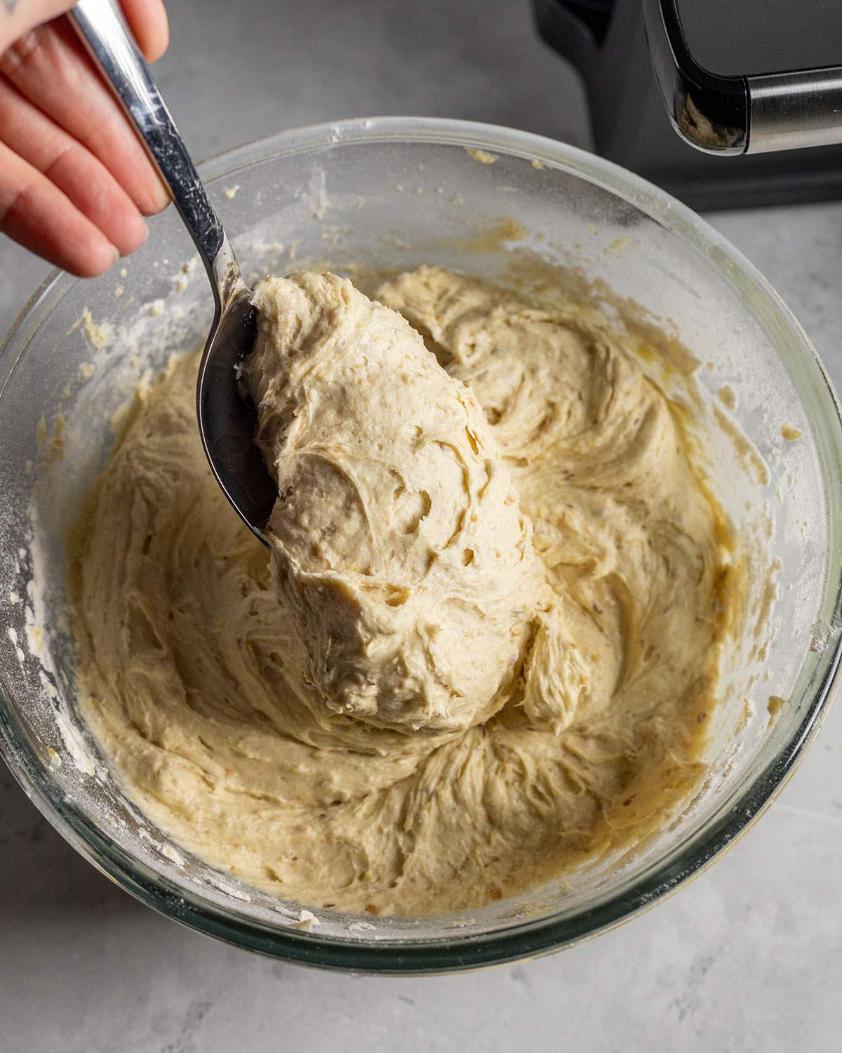 a spoon portioning waffle batter out of a mixing bowl