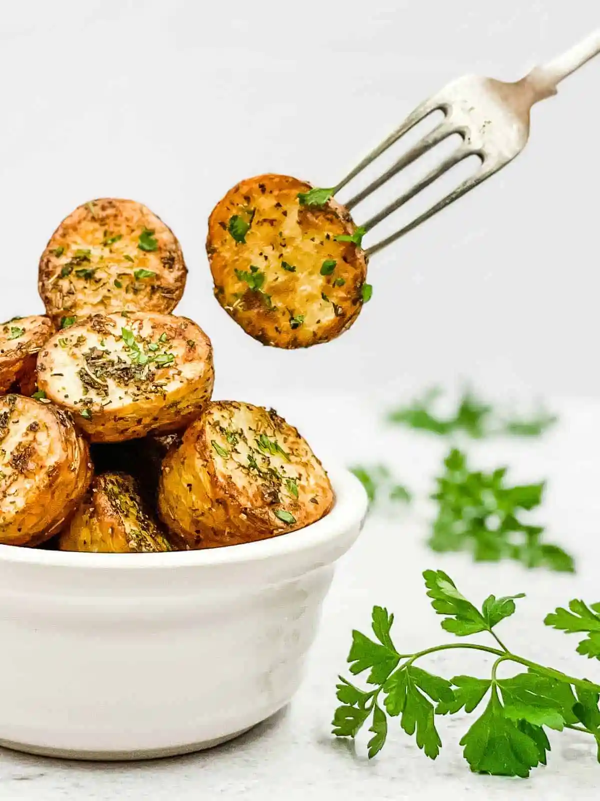 a bowl filled with crispy air fried baby potatoes and a fork picking up a potato from the bowl