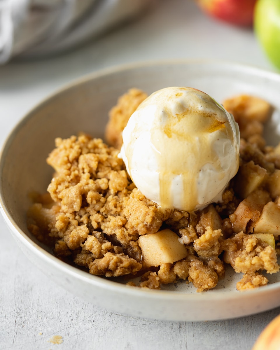 A bowl with vegan apple crumble and vegan ice cream on top