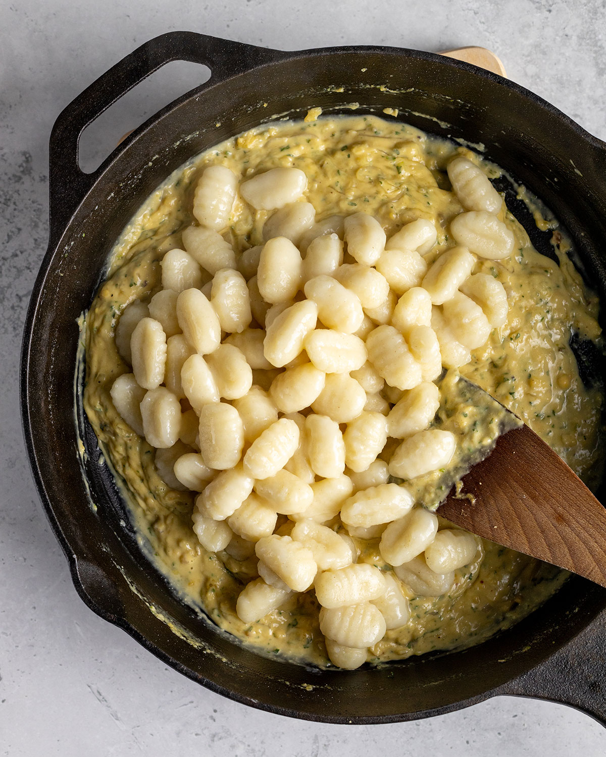 gnocchi added to a skillet with carbonara sauce