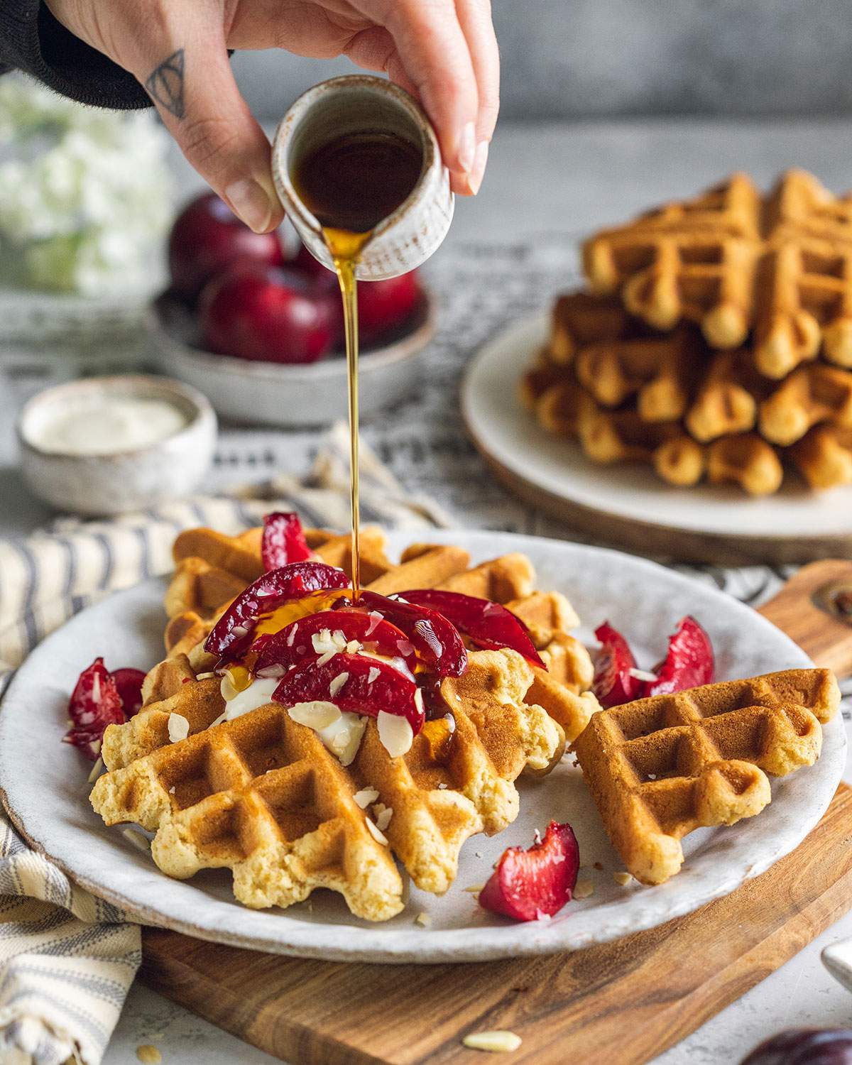 maple syrup being poured onto a stack of condensed milk waffles