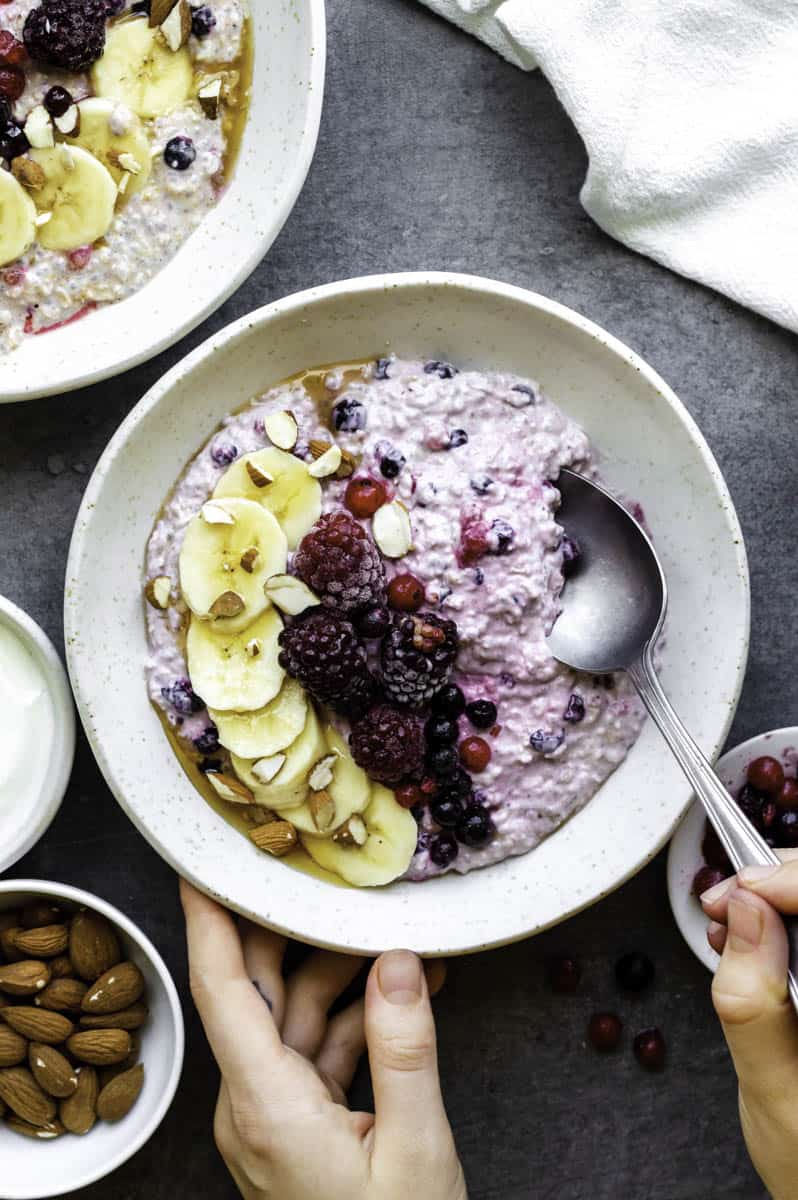 a beautiful bowl filled with overnight oats and frozen fruits on top