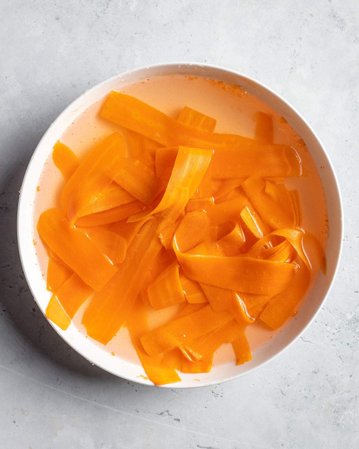rinsing carrot strips in a bowl