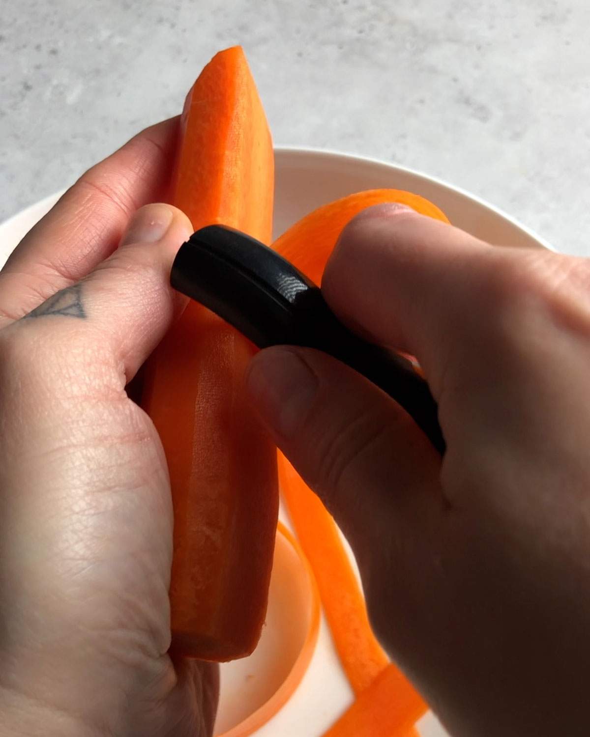 shaving a carrot with a vegetable peeler