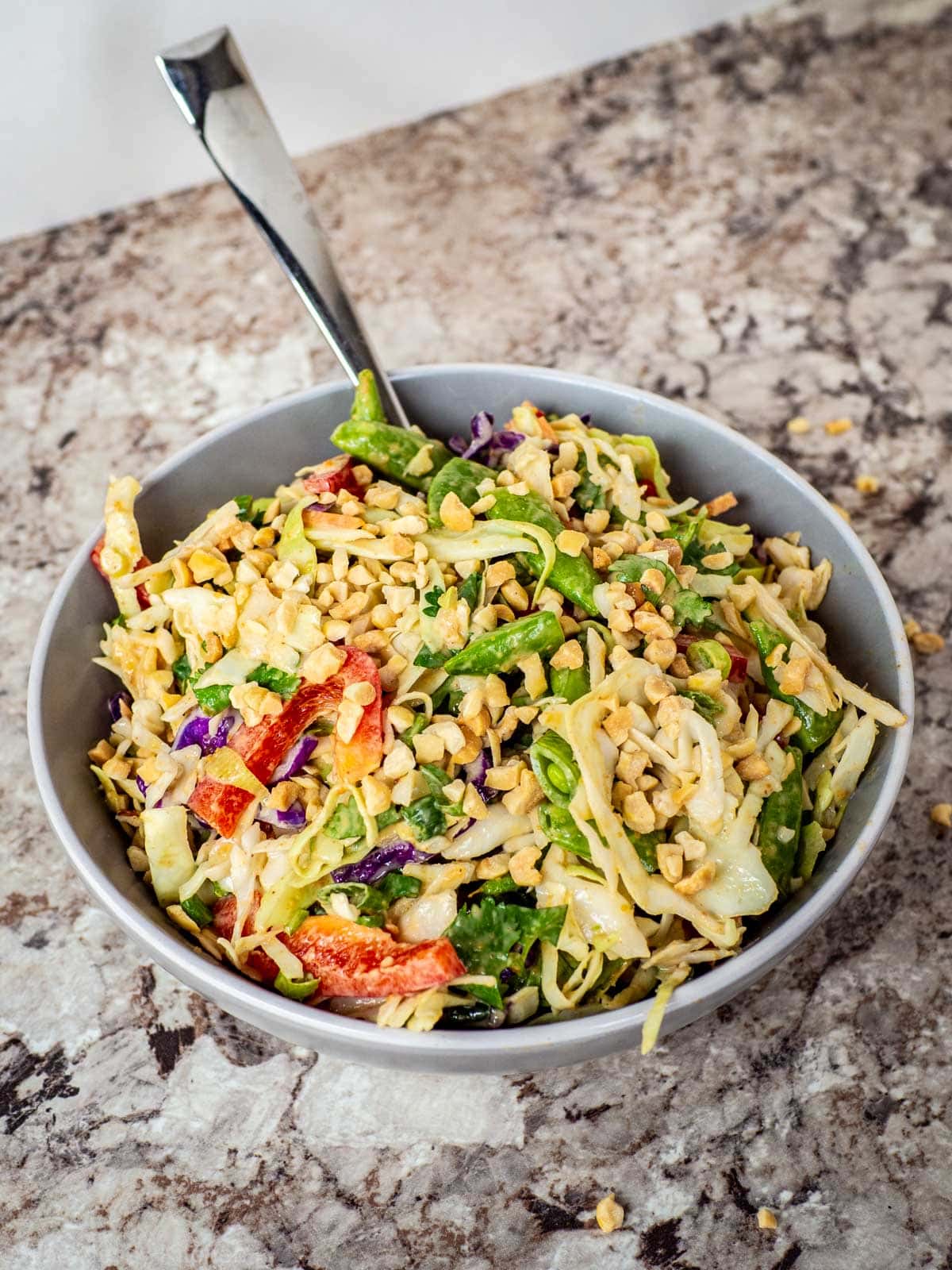 a bowl filled with thai peanut salad on a kitchen counter