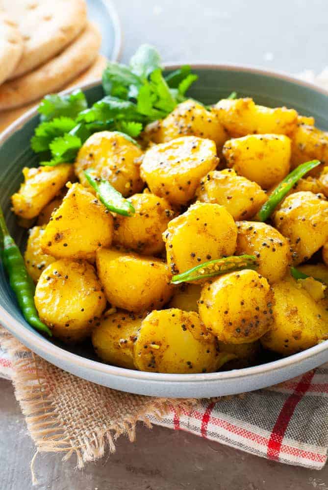 a serving bowl filled with vegan bombay potatoes