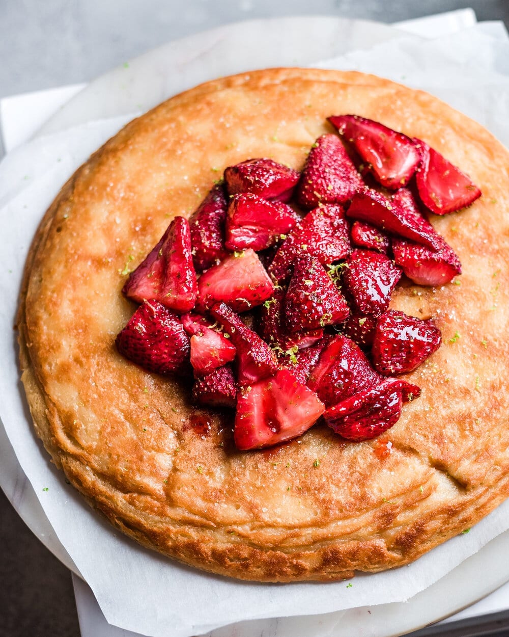 fluffy vegan dutch baby on a plate topped with strawberries