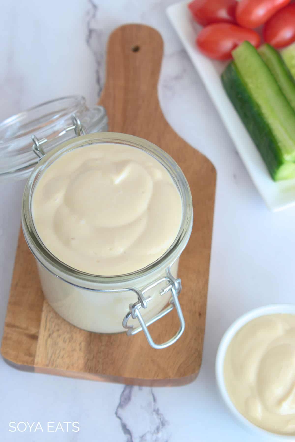 an open jar filled with homemade vegan mayo on a wooden board