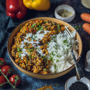 vegan red lentil dhal with rice in a yellow bowl on a dark table