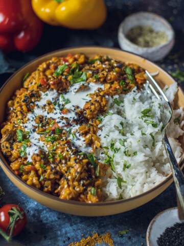 vegan red lentil dhal with rice in a yellow bowl on a dark table