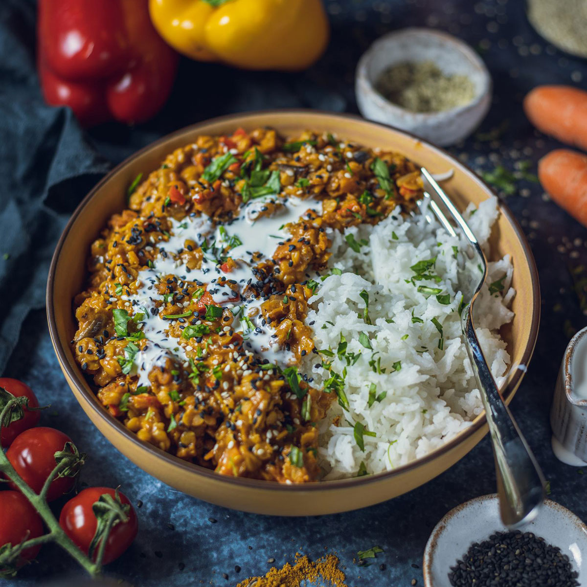 vegan red lentil dhal with rice in a yellow bowl on a dark table